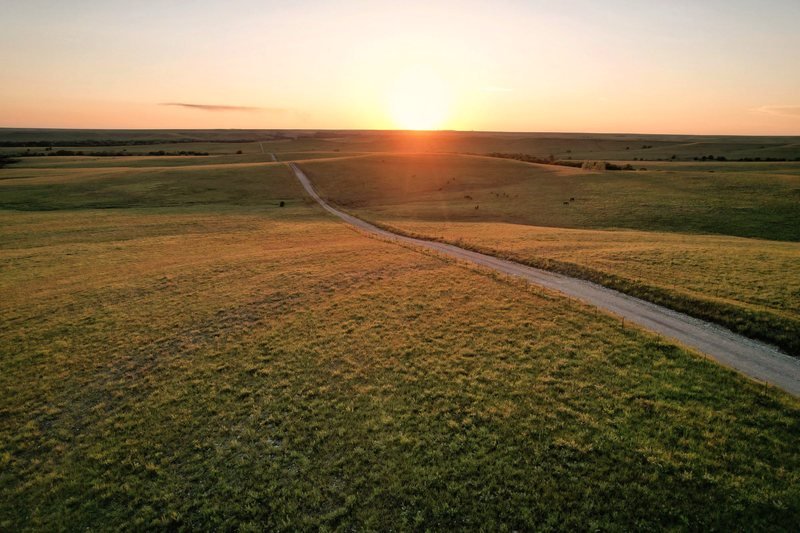 A dirt road crossing open prairie at sunset in Kansas
